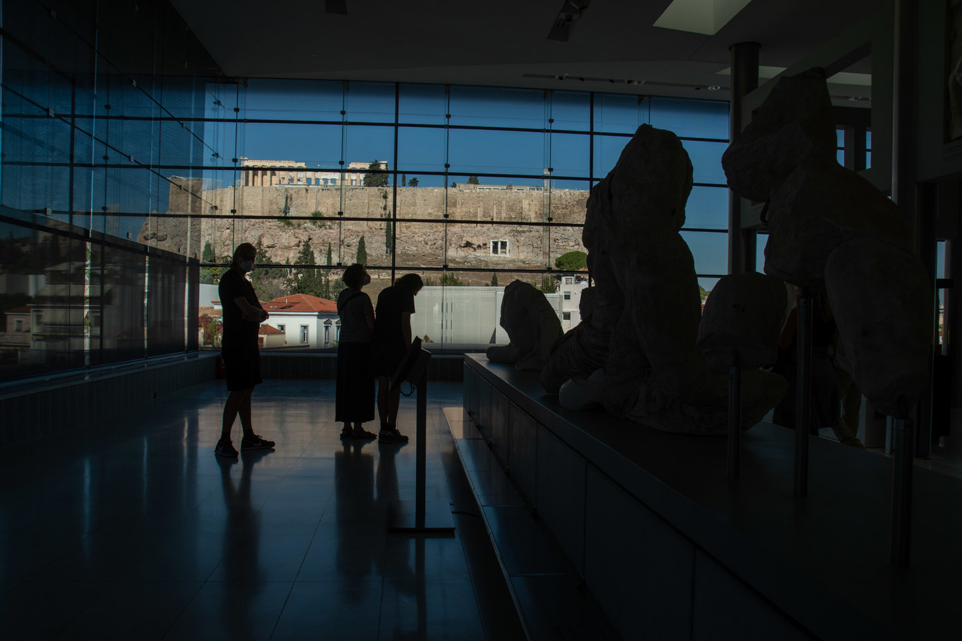 View from the Acropolis Museum to the Acropolis rock with the Parthenon. In the foreground, the sculpture exhibition in the semi-darkness.