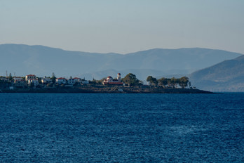 View from Marathonas beach to the neighboring village of Peridka with Sozon Church on a headland.