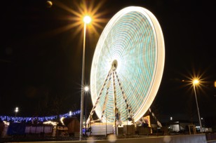 Long exposure of a rotating Ferris wheel at night on an abandoned fairground 
