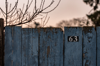 Blue wooden board fence with house number 