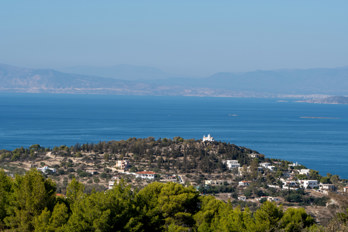 View from a hill in the north of Aegina towards the northwest. The Church of the Prophet Elias and St Nicholas stands dominant on a hill. In the background is the Gulf of Megara, the northern part of the Saronic Gulf.