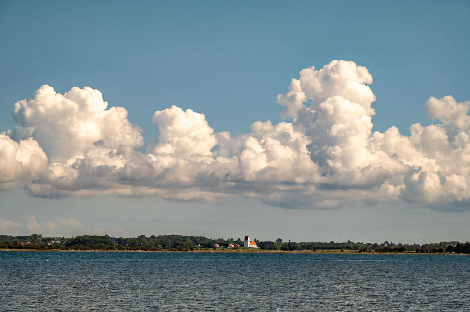 Cumulus clouds over Fanefjord Kirke on the island of Møn. View of the sea from the island of Falster.