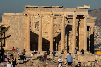 The Erechtheion on the Acropolis illuminated by the morning sun with a few tourists.