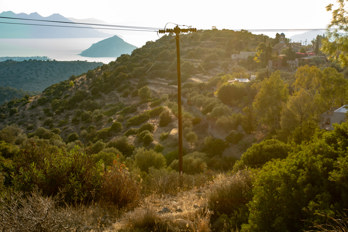 View of the village of Pachia Rachi with the church of Agios Dionysios above terraced fields on the island of Aegina. In the background, the Saronic Gulf with the island of Moni.