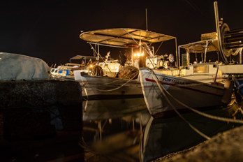 Long exposure shot of fishing boats in the harbor of Aegina at night.