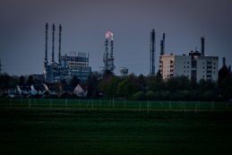 Flames at the onset of night. In the foreground fields and residential buildings.