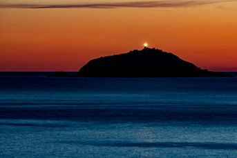 View from Tellaro to the island Isola del Tino after sunset with the lighthouse Faro di San Venerio