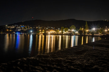 Long exposure shot of Marathonas Bay at night from a jetty. Due to the closed aperture, the lights appear as stars.