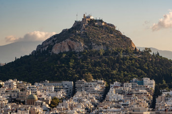 Mount Lycabettus seen from the Acroplis with a telephoto lens. Houses below, a green park above and the chapel of St. George on top of the rock.