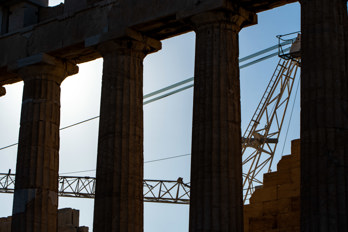 The silhouette of the columns of the Pantheon with the construction crane on the Acropolis in the morning sun.