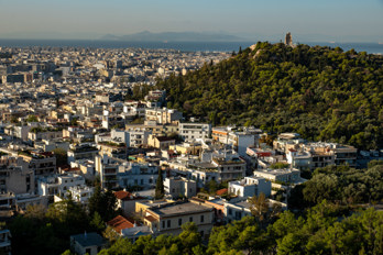 View from the Acropolis over Athens in southern direction. On the right the Philopappos Monument and in the background the island of Aegina in the Saronic Gulf.