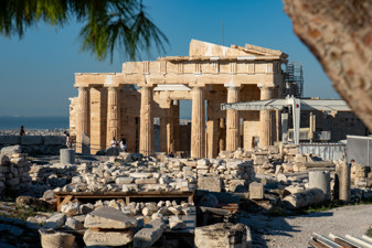 View from the Erechtheion to the Propylaia. A construction crane on the right and stacked stones in the middle.