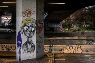 Sad graffiti face on a column under a bridge