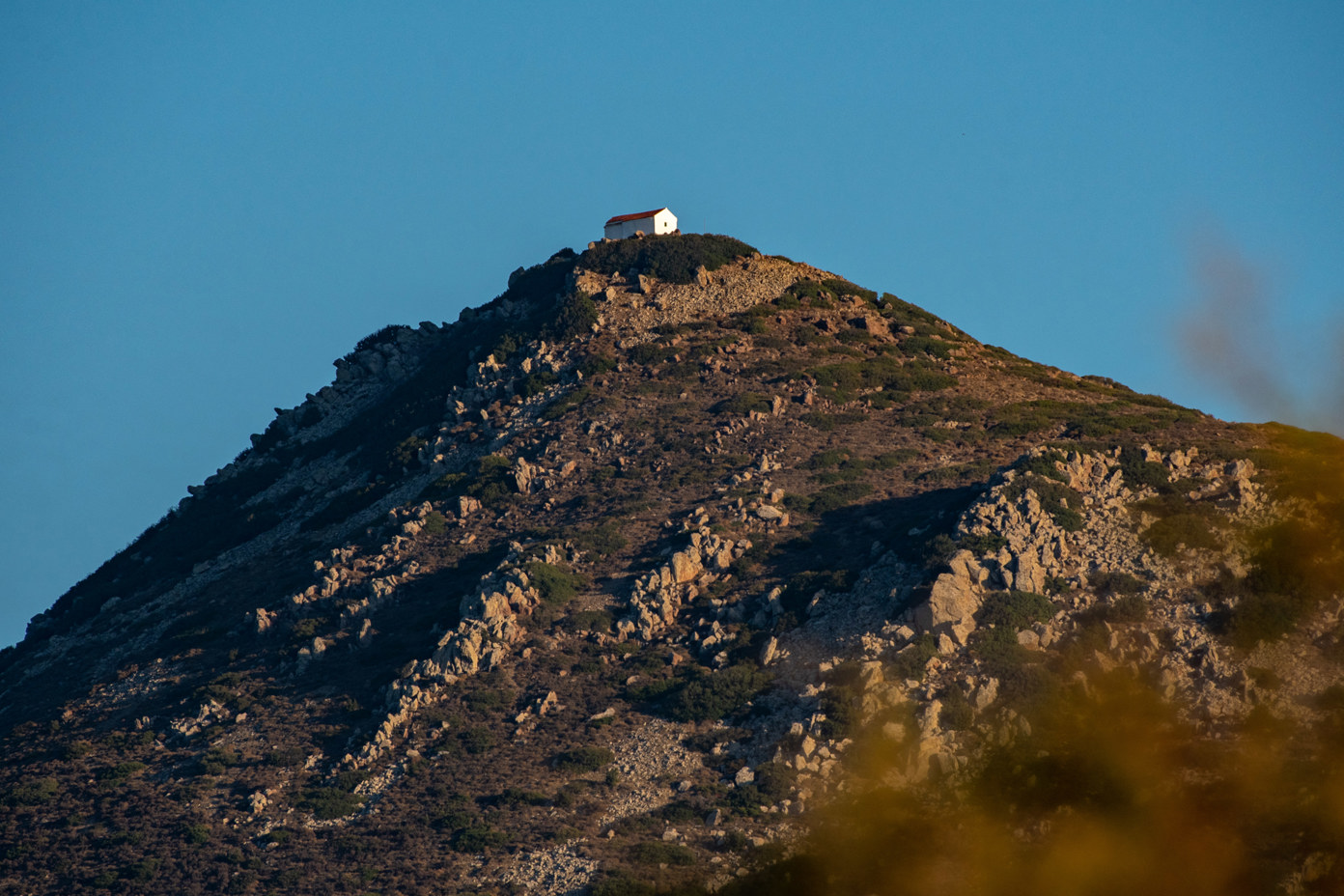 Peak of Hellanion Oros with the Chapel of Prophet Elias on the island of Aegina in Greece with an altitude of 532m. Taken with a long lens from Marathonas beach.