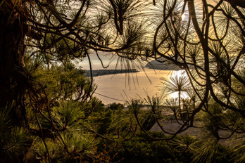 View from the settlement of Aiginitissa on the island of Aegina across the Saronic Gulf. On the left the town of Perdika on a headland and in the centre the uninhabited island of Moni at sunset.