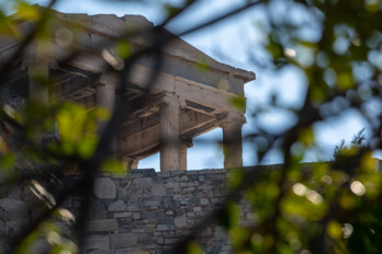 View from the north, from the old town, through the leaves to the entrance area of the Temple of Erechtheion on the Acropolis Rock.