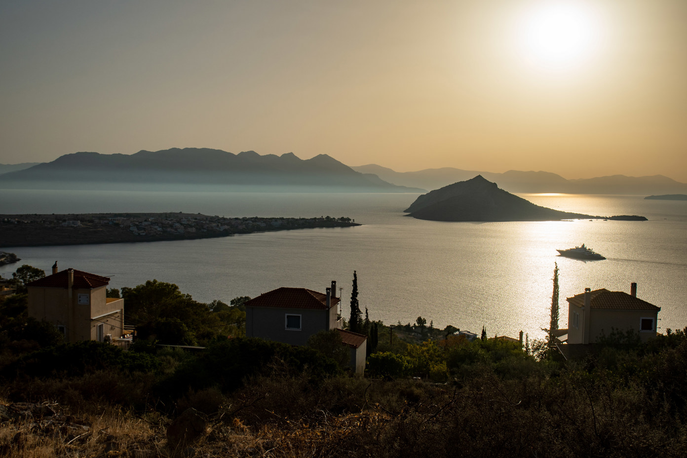 View over the Saronic Gulf from the hill of the settlement of Aiginitissa on the island of Aegina. The upper houses of the settlement can be seen in the foreground. On the left is the town of Perdika on a headland. The uninhabited island of Moni can be seen in the centre.